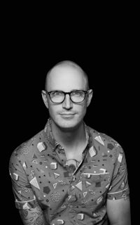 a black and white photo of a bald man with glasses